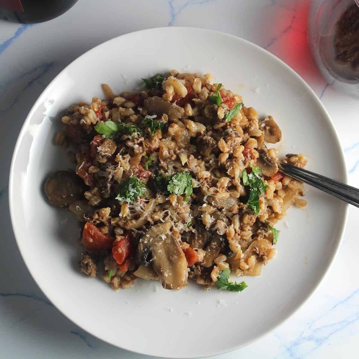 farro with mushroom and ground beef on a white plate