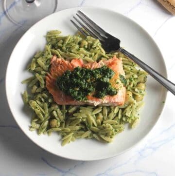 salmon served on a bed of orzo, topped with pesto.