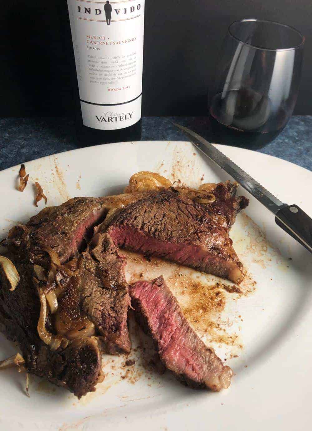 platter with ribeye steak and red wine in the background.