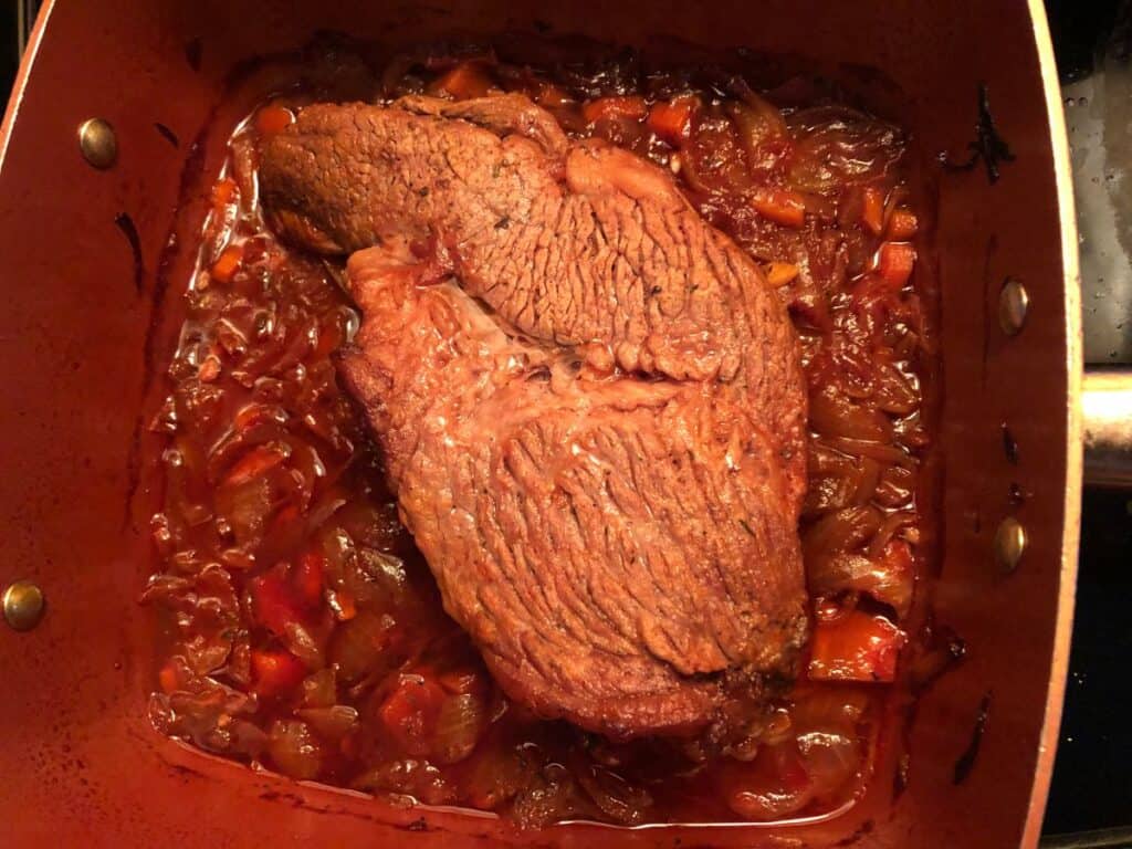 small brisket cooking in a copper pan.