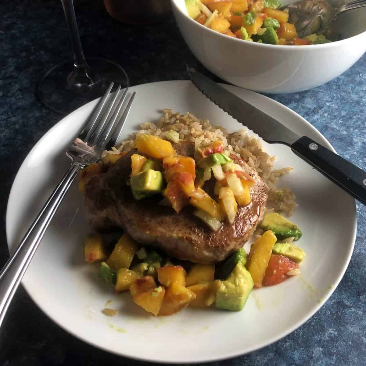 pork chops topped with a peach avocado salsa