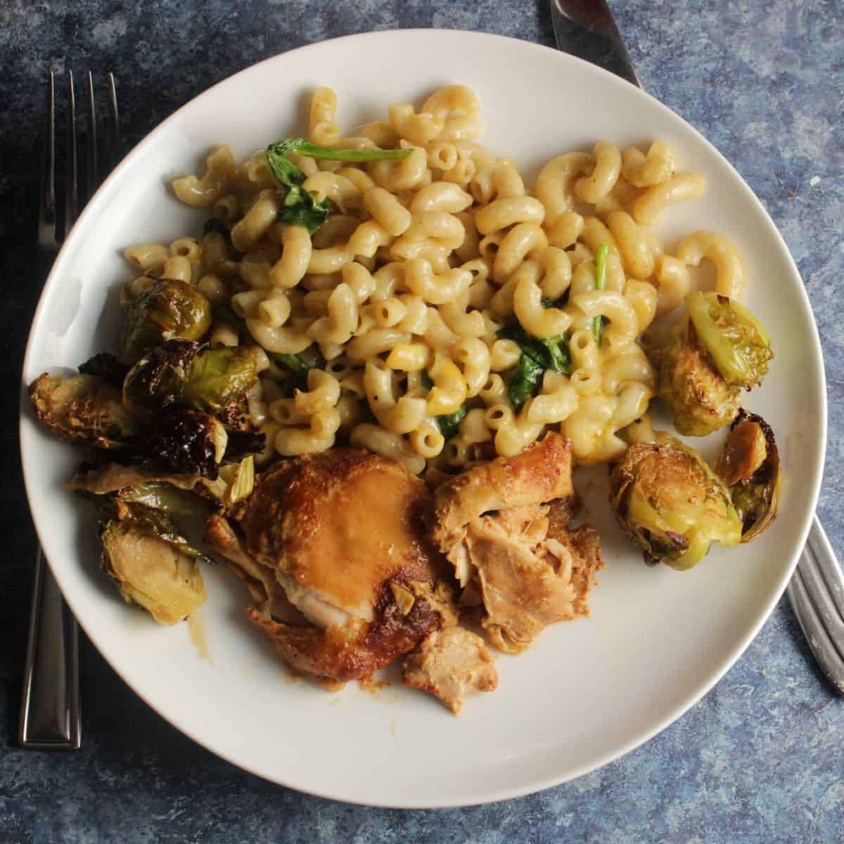 slow cooker BBQ chicken thighs served with pasta and Brussels sprouts.
