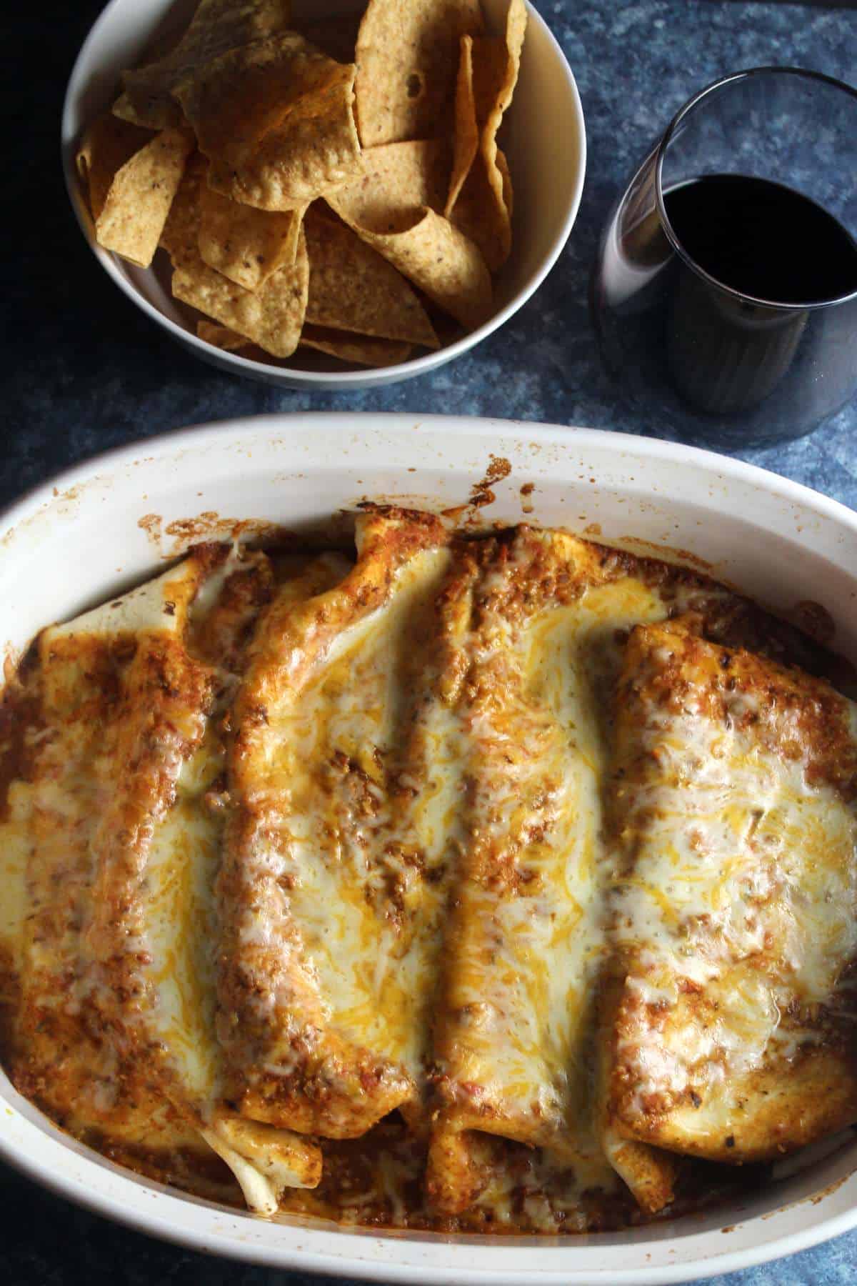 beef and black been enchiladas with melted cheese, in a white baking dish.