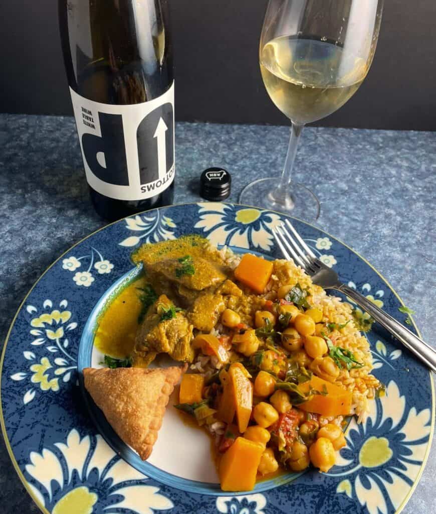 Indian food on a plate with Bottoms Up white wine.