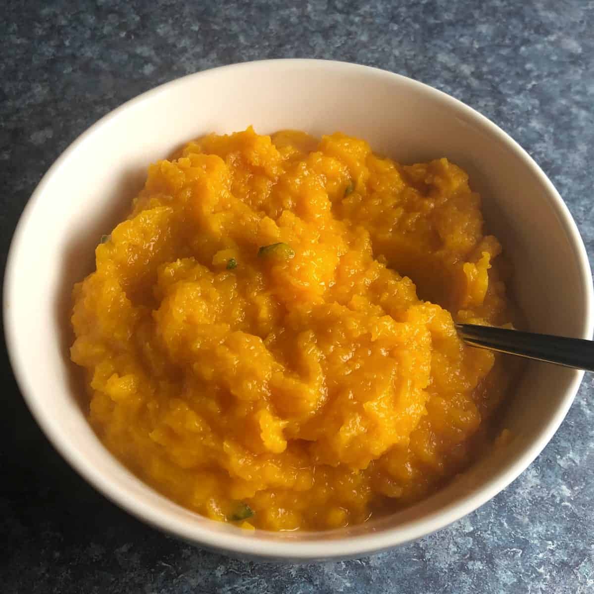 savory mashed butternut squash served in a white bowl.