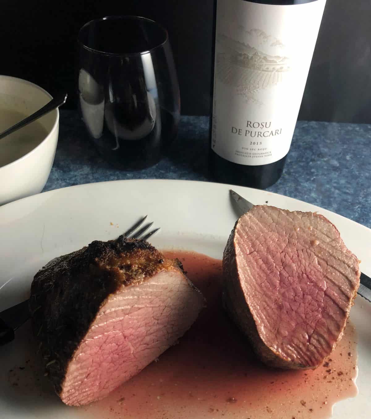 medium rare roast beef sliced in half with a red wine in the background.