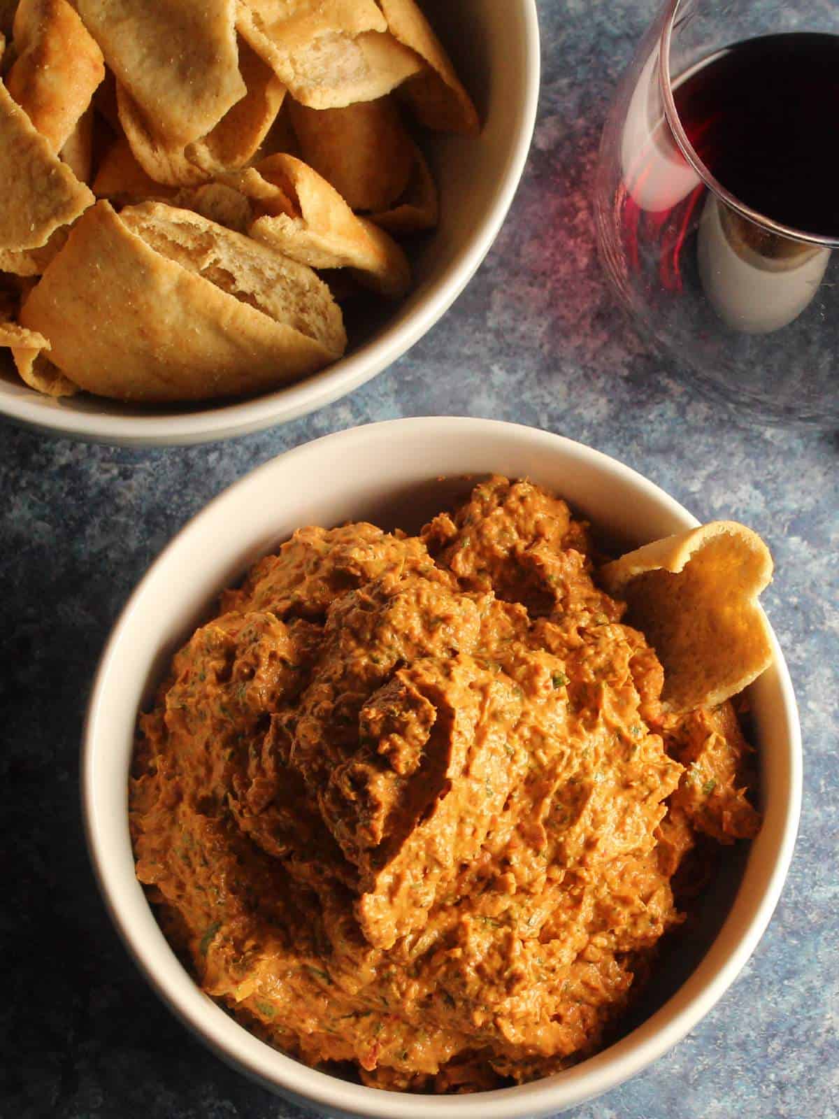 bowl of roasted red pepper dip from above, in a white bowl, served with pita chips.