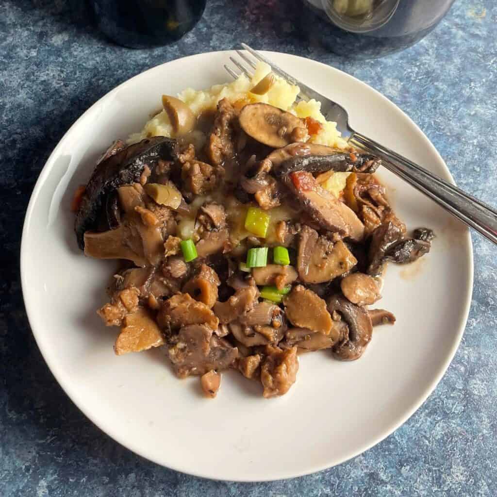 mushroom friccassee served over mashed potatoes on a white plate