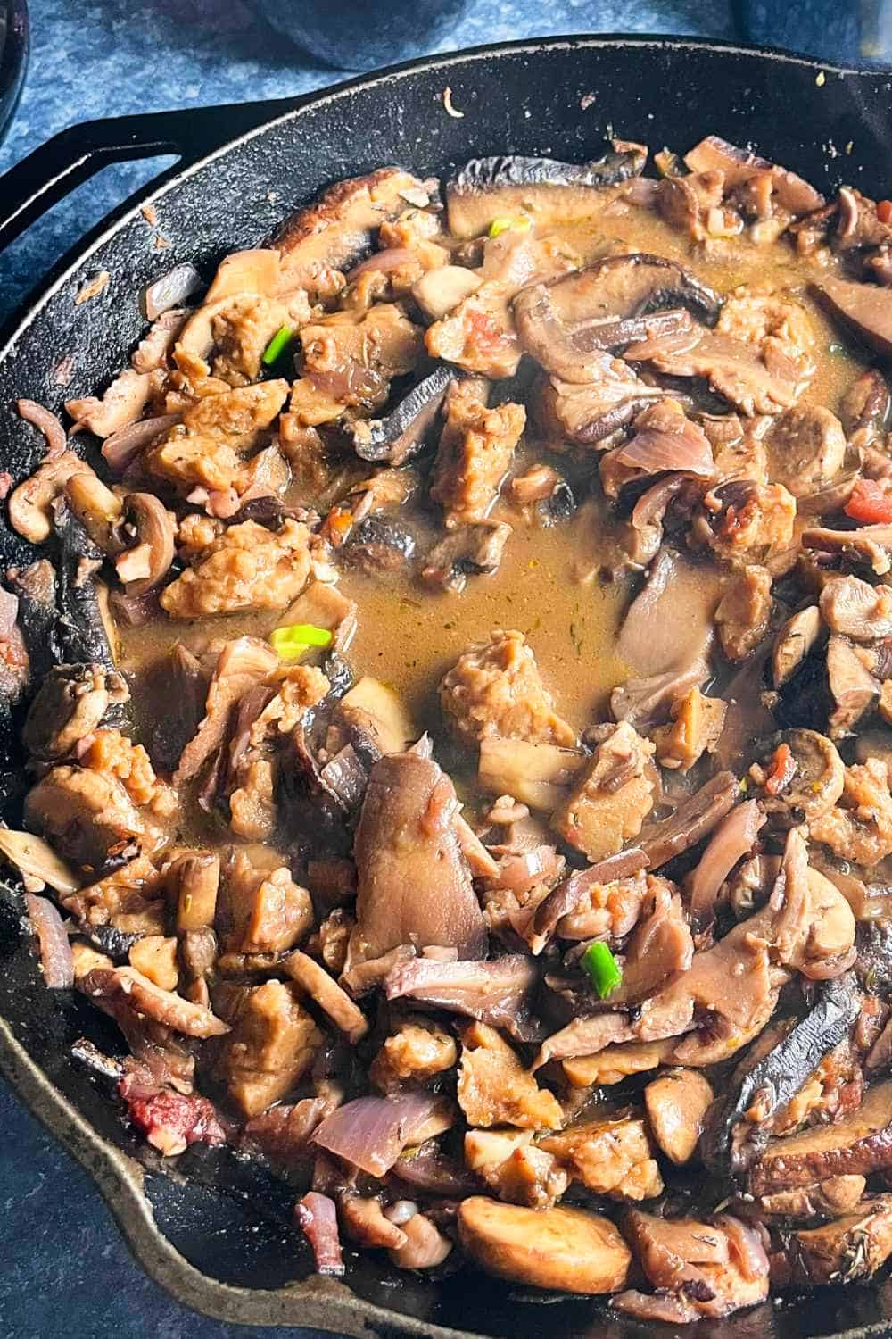 close up of mushrooms cooked in a black skillet with red wine sauce