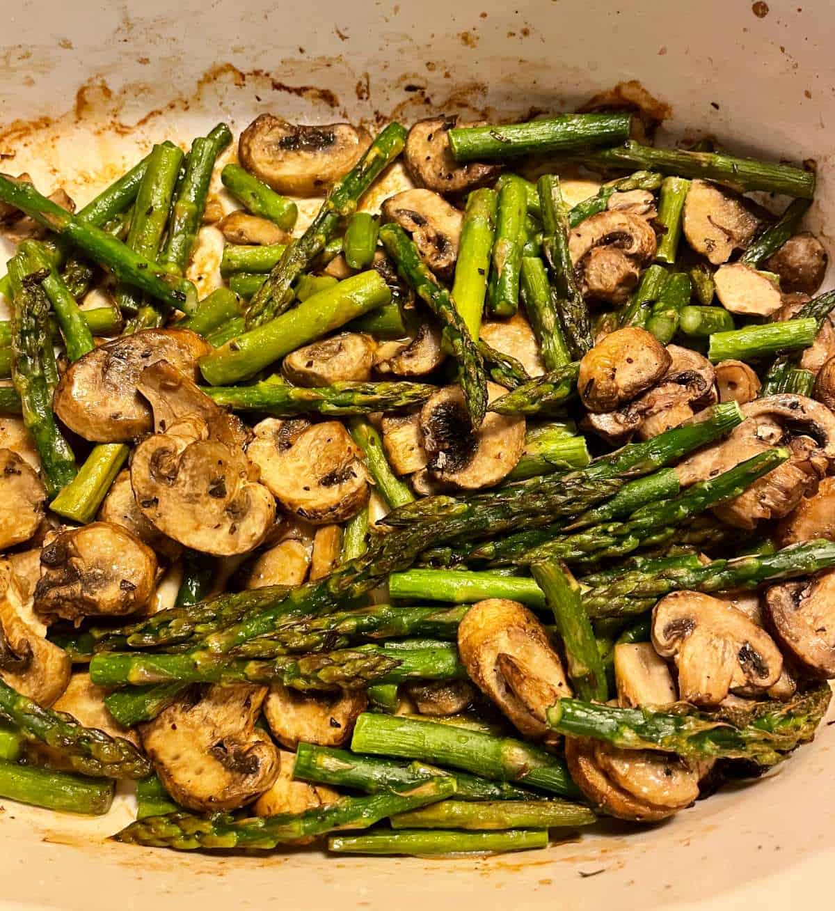 roasted asparagus and mushrooms in a white baking dish. 