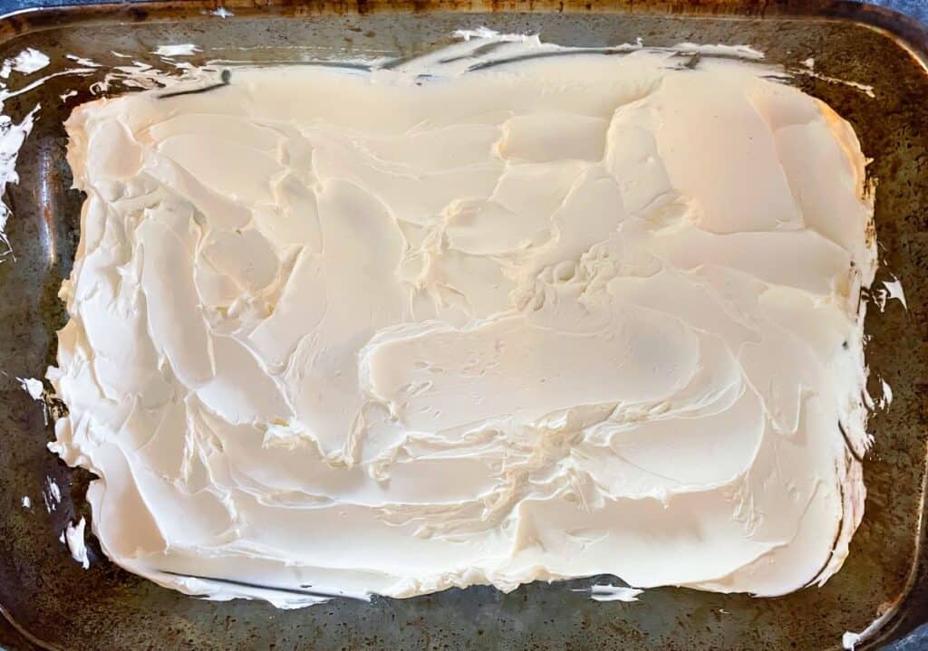 cream cheese spread out in the bottom of a baking dish.