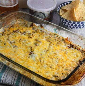 mexican dip topped with melted cheese in a baking dish.