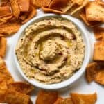 hummus in a white serving dish served with pita chips.