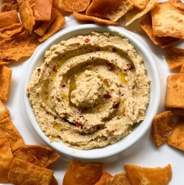 hummus in a white serving dish served with pita chips.