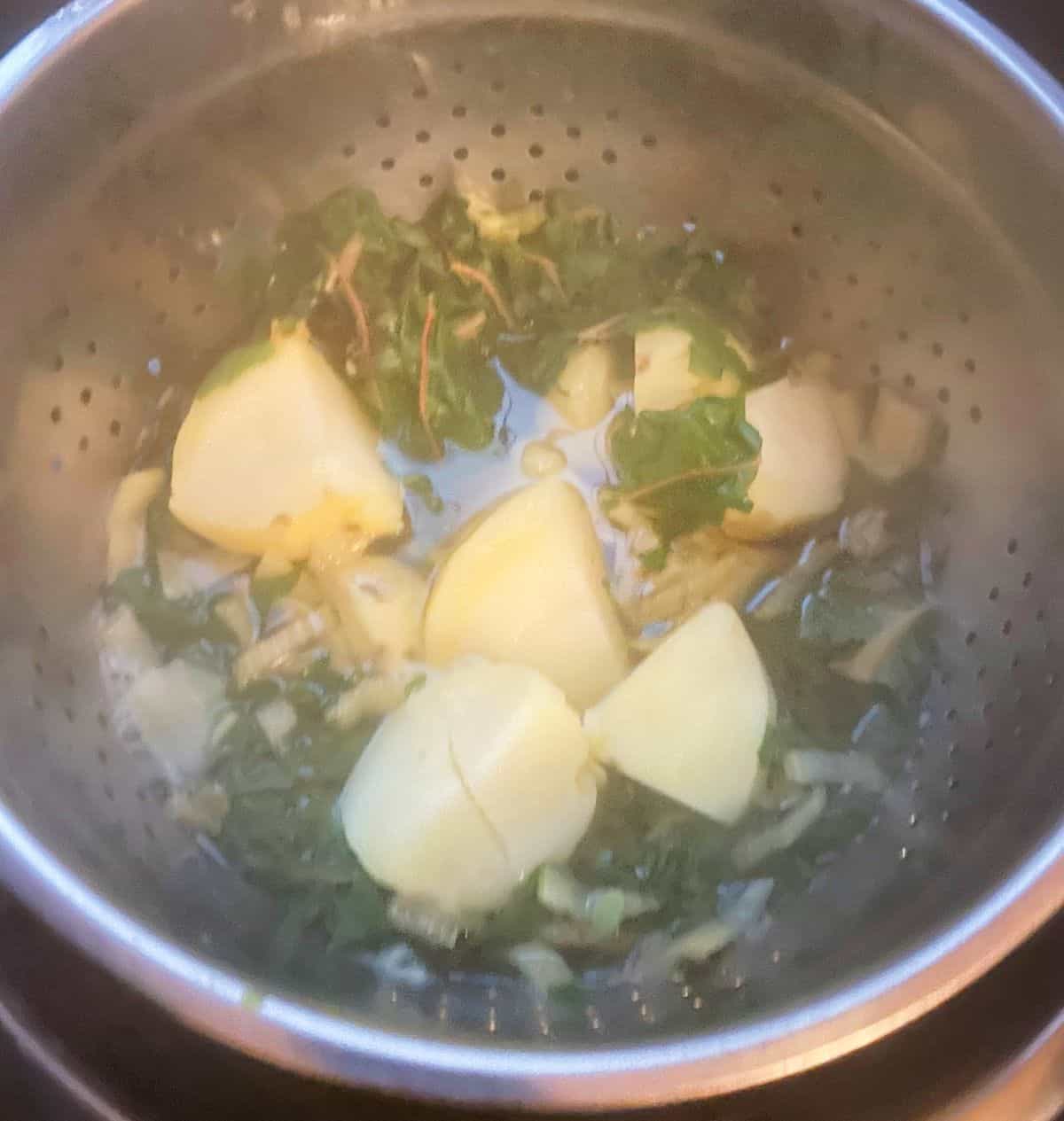 cooked potatoes and chard draining in a colander.