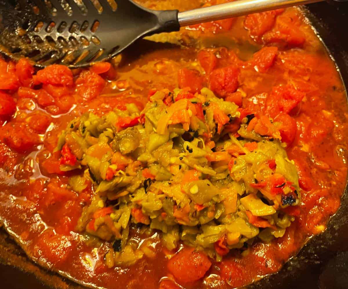 Hatch Chiles added to a skillet with diced tomatoes simmering.