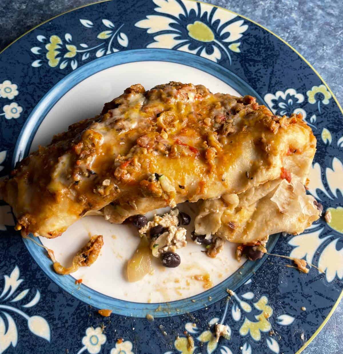 vegetarian Hatch chile enchilada served on a plate with flowers around the edges.