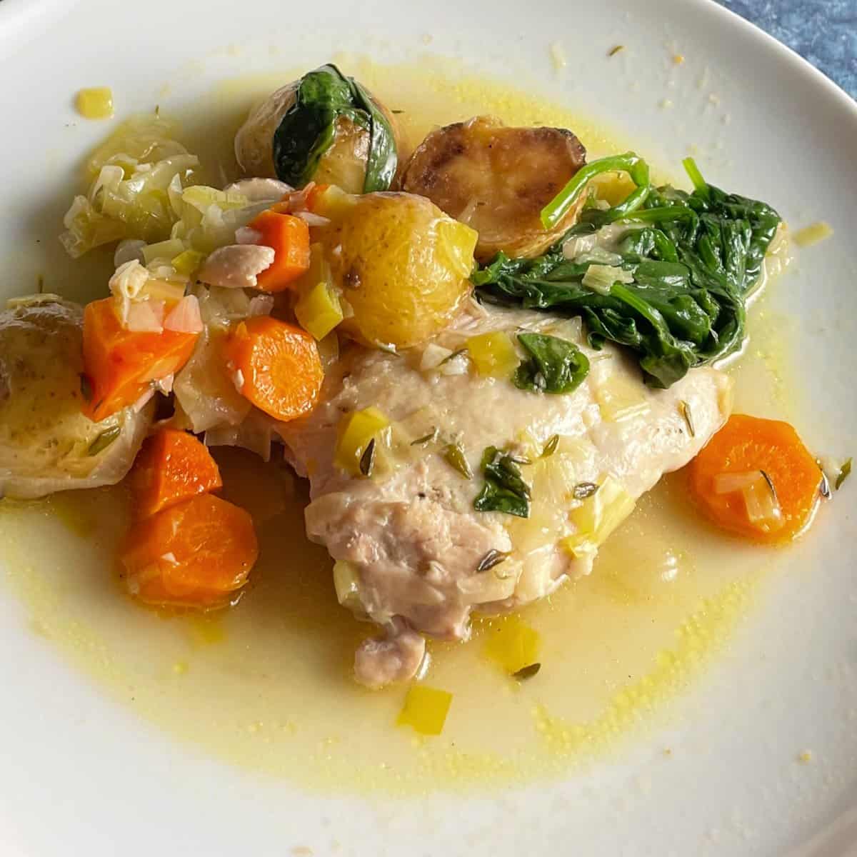 braised chicken thighs with vegetables on a white plate