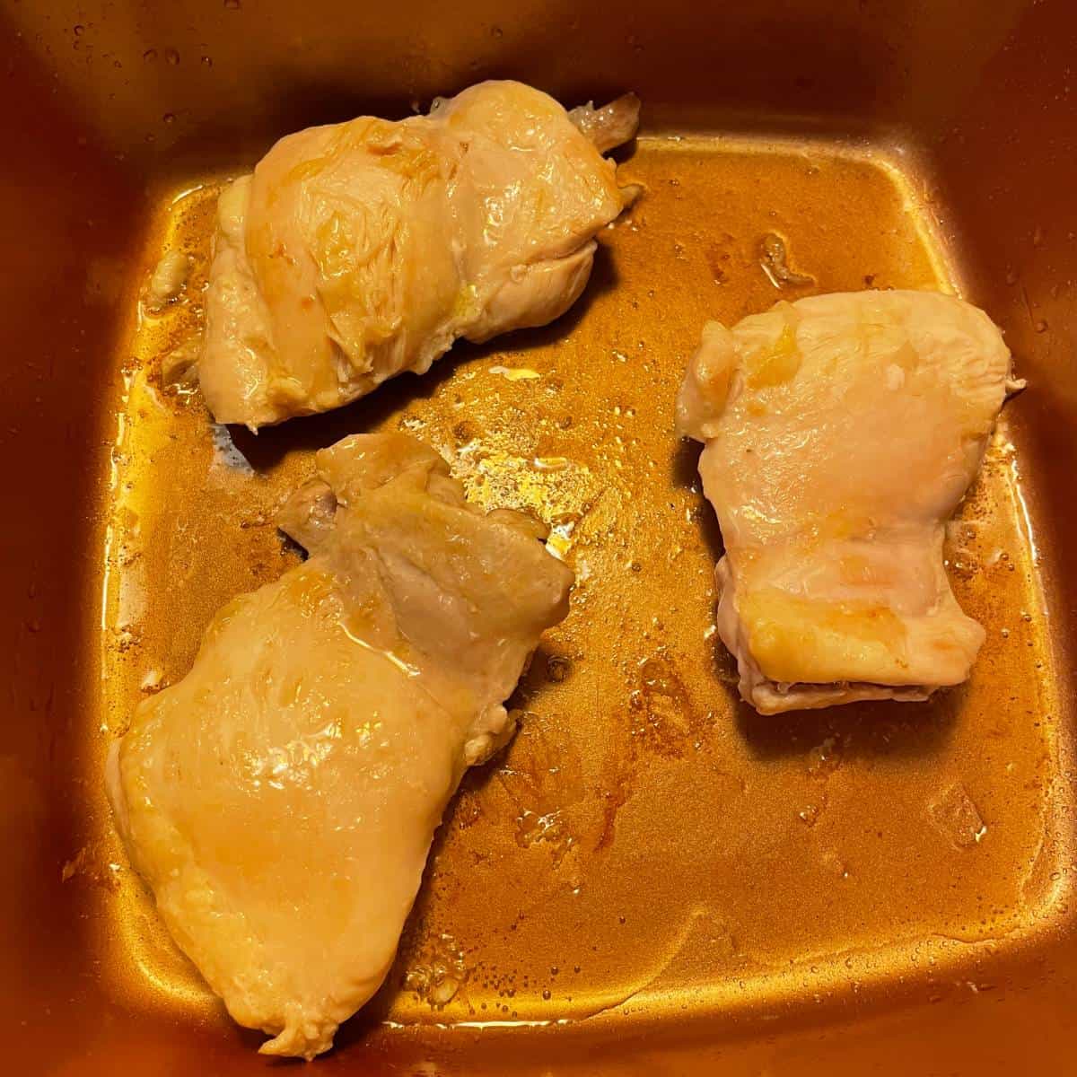 browning chicken thighs in a copper chef pan.