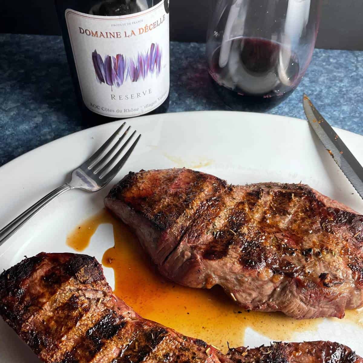 Grilled sirloin steak on a white platter served with a Cotes du Rhone red wine.