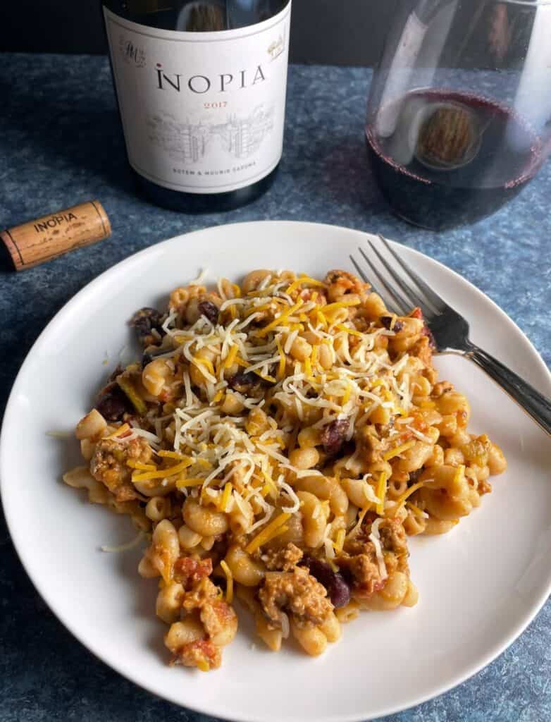 chili mac & cheese on a white plate served with a red Cotes du Rhone wine.