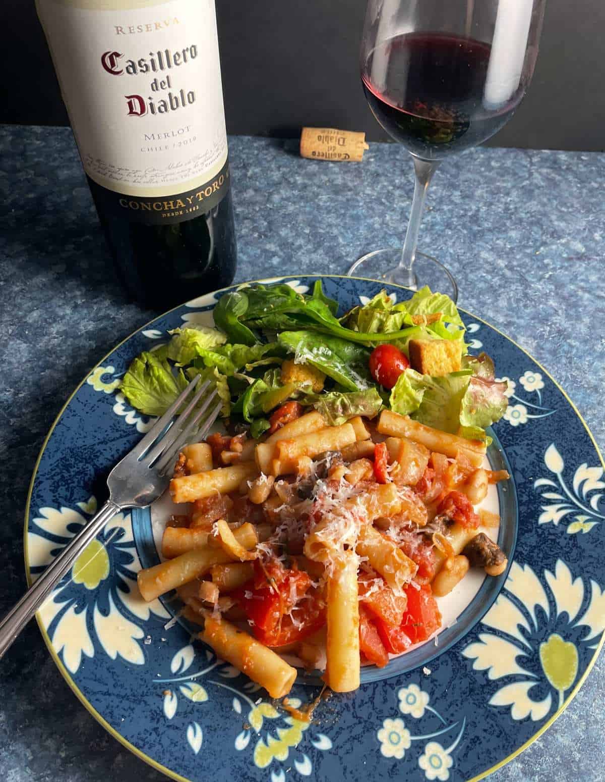 ziti pasta with tomato sauce and white beans, served with a side salad and a Merlot red wine.