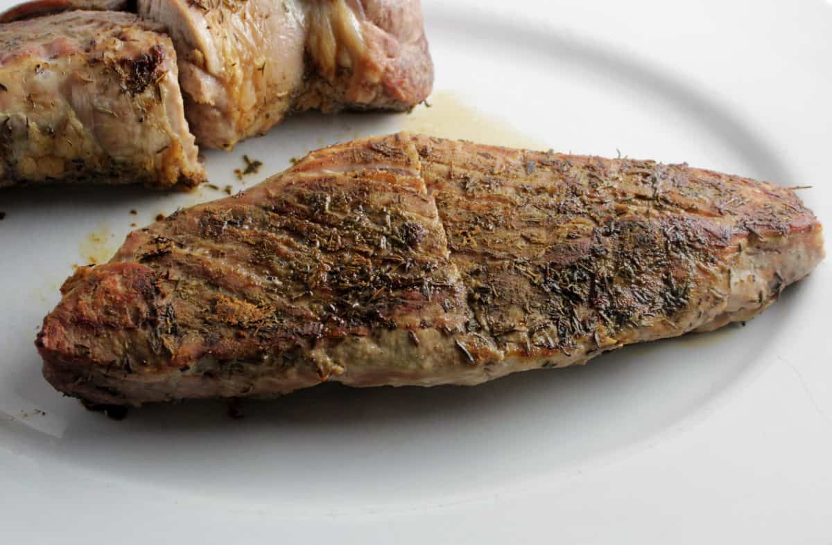roasted pork tenderloin resting on a white platter.