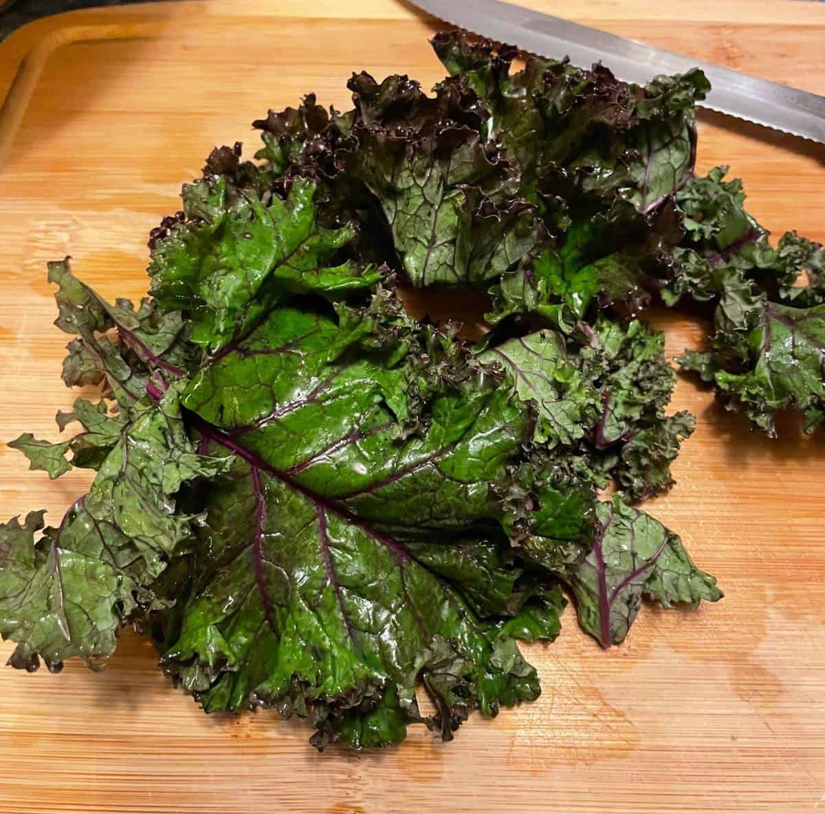 purple kale on a wooden cutting board.