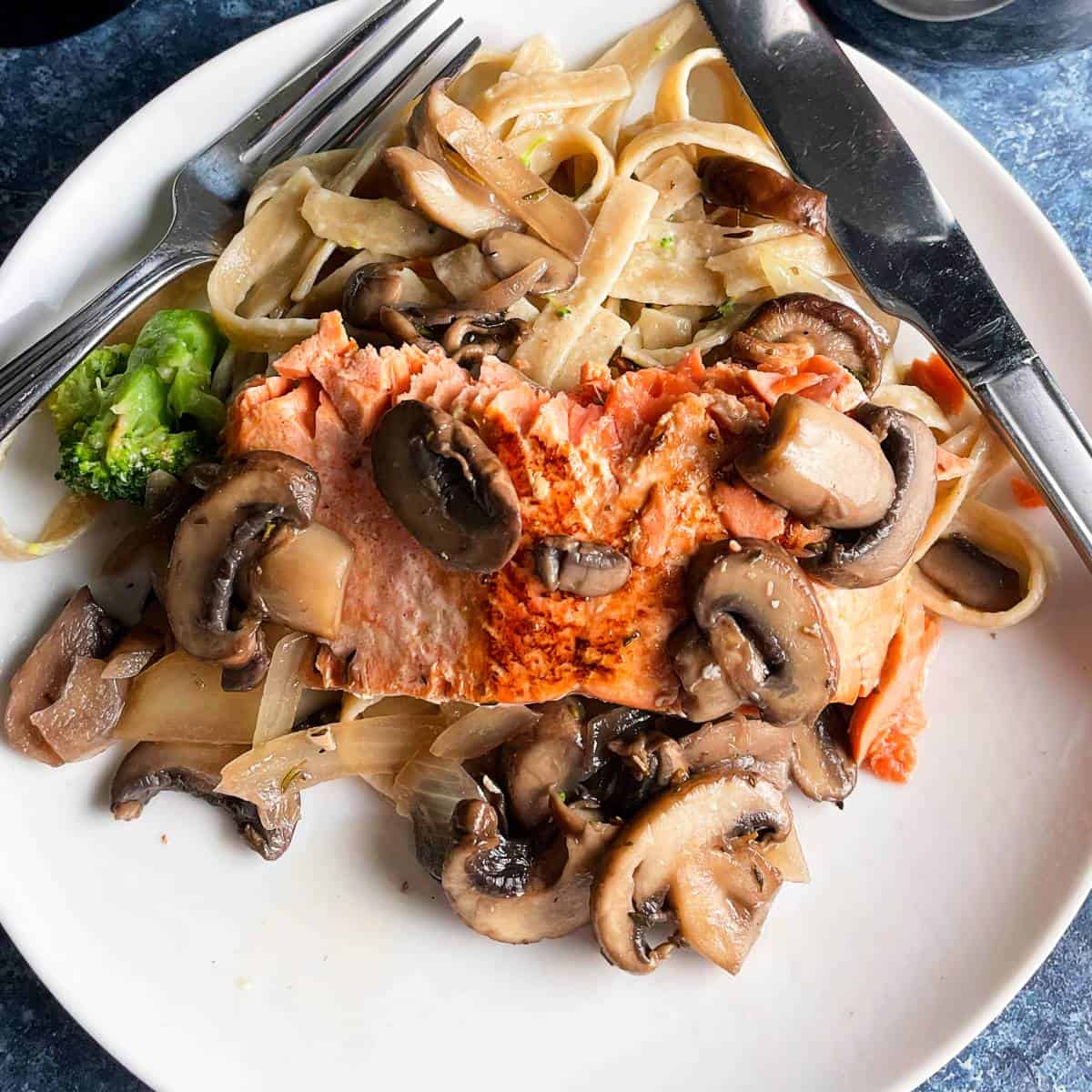salmon topped with mushrooms, served with pasta.