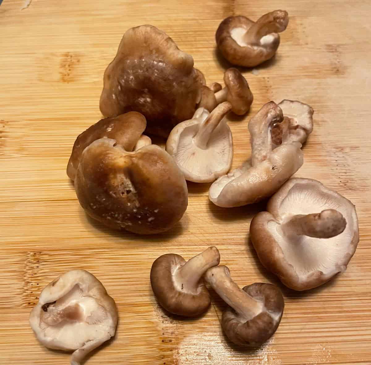 small shiitake mushrooms on a cutting board.