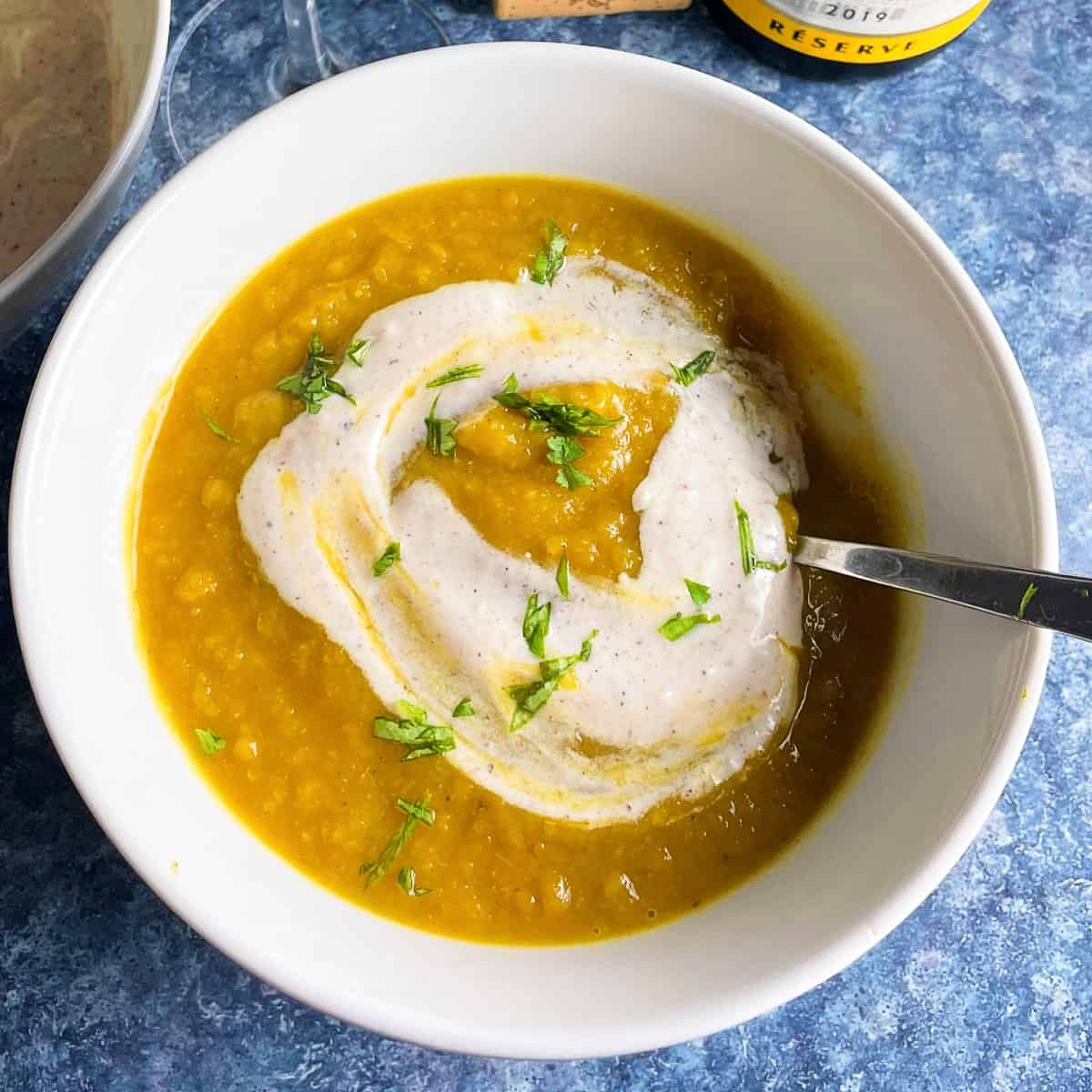 curried acorn squash soup in a white bowl, topped with a swirl of yogurt.