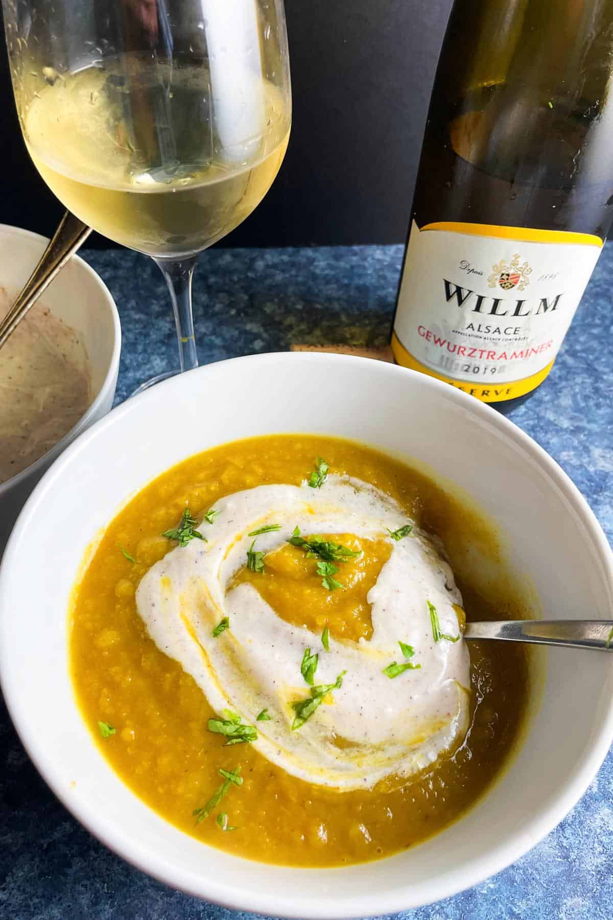 curried acorn squash soup with a swirl of yogurt on top, served with a bottle of gewurztraminer wine.