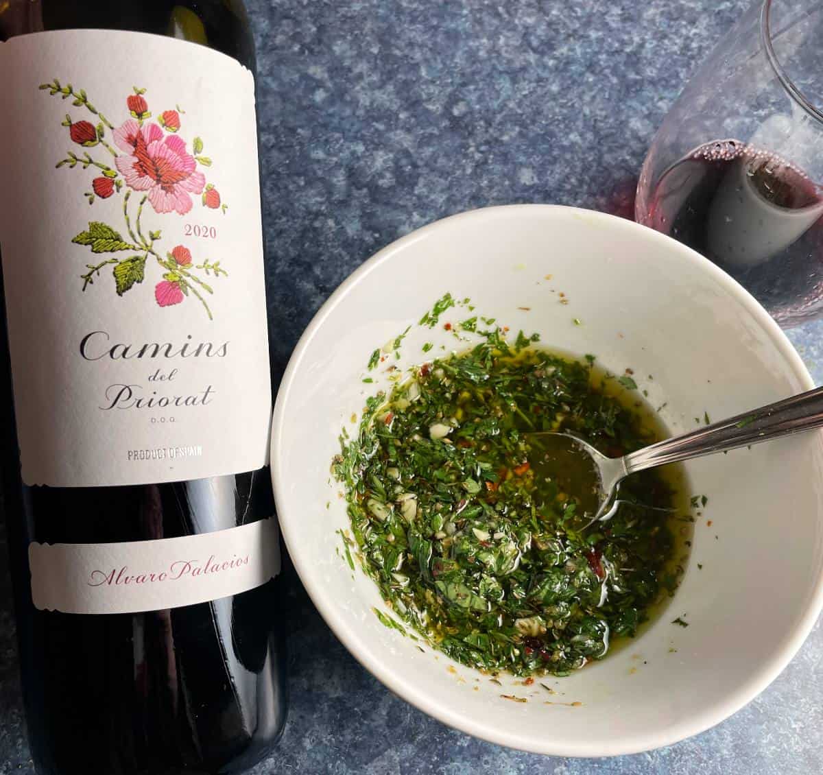 bowl of carrot top chimichurri along with a bottle of Priorat red wine.