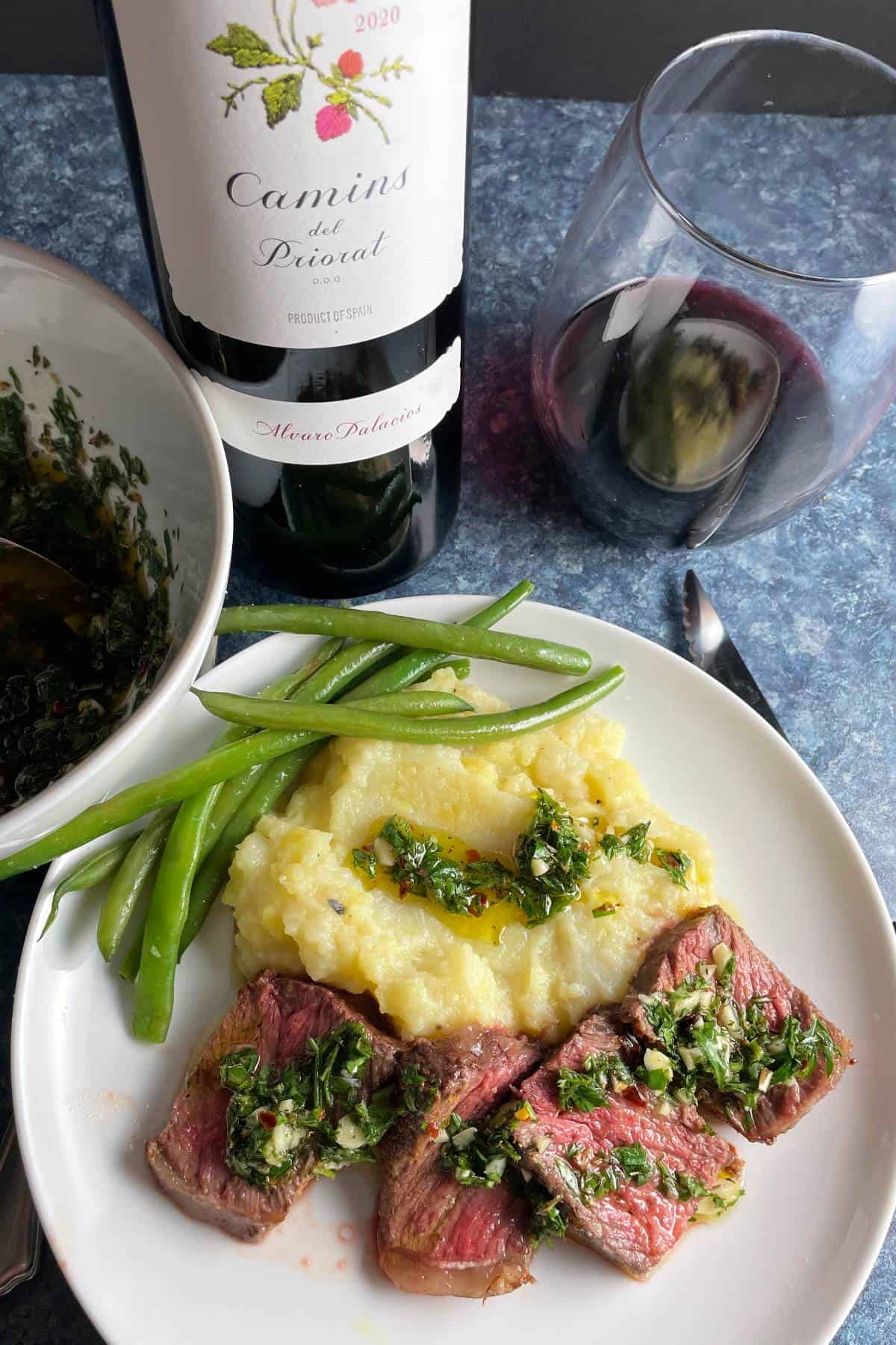 slices of steak topped with chimichurri, served with mashed potatoes and green beans along with Spanish red wine.