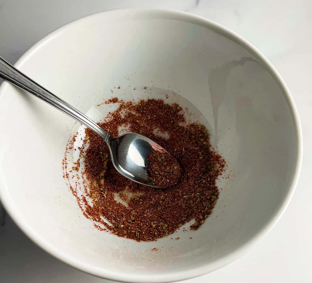 Combining fajita spice blend ingredients in a white bowl.