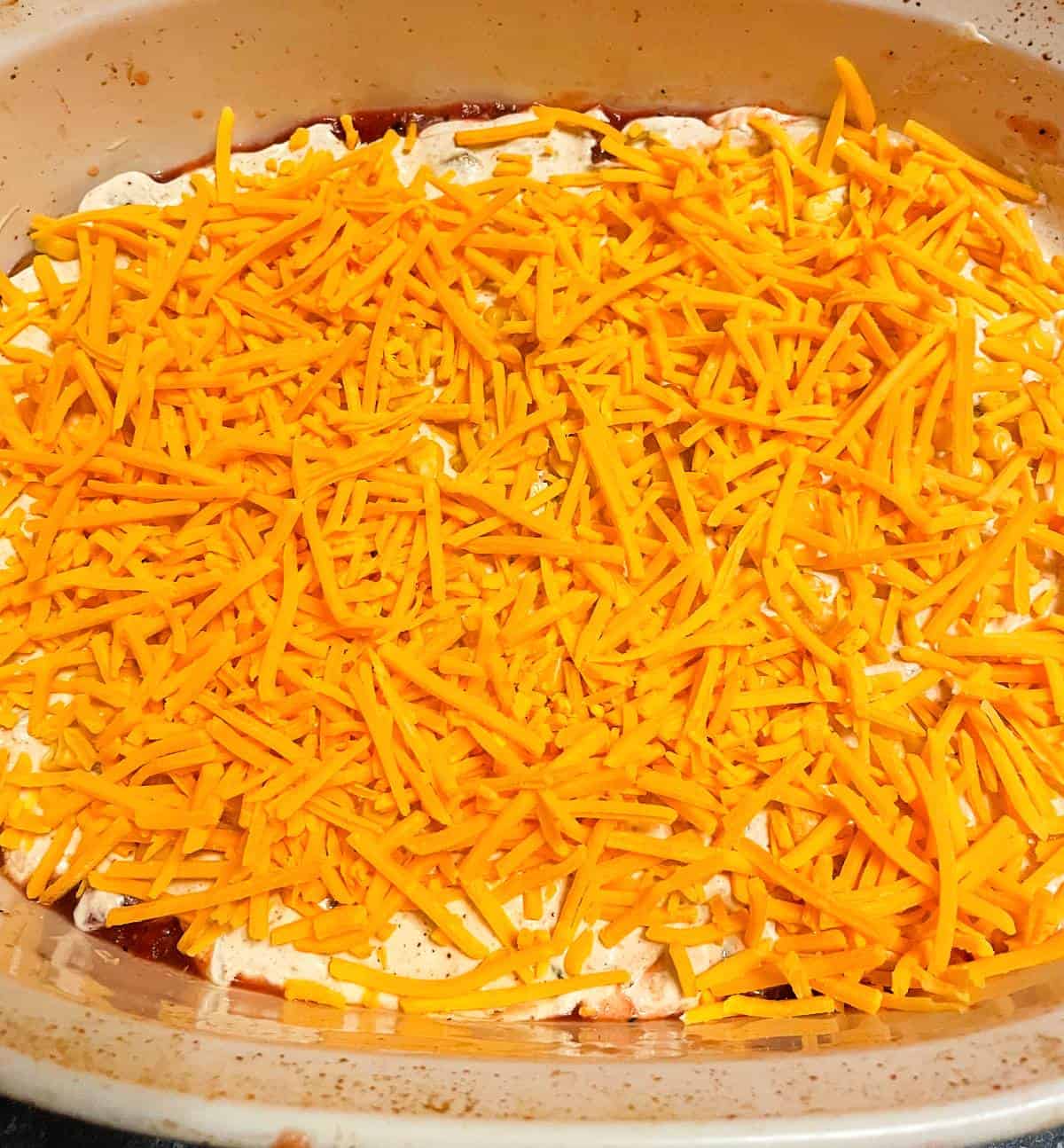 shredded cheddar cheese covering the other ingredients for baked fiesta dip. 