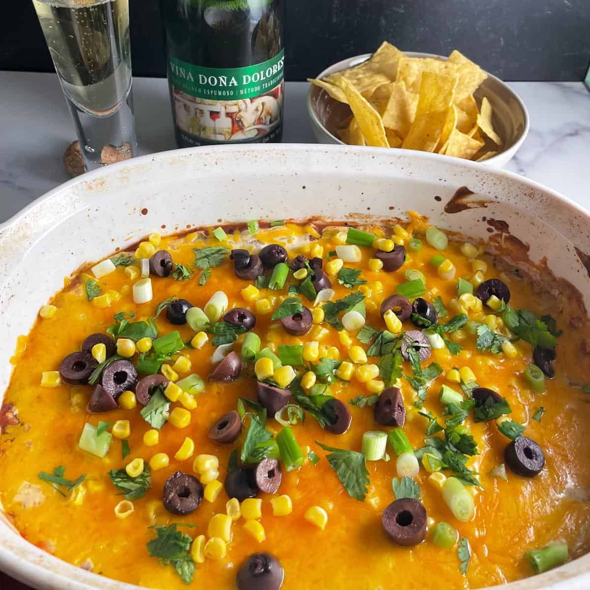 baked fiesta dip in a white baking dish, served with sparkling wine from Mexico.