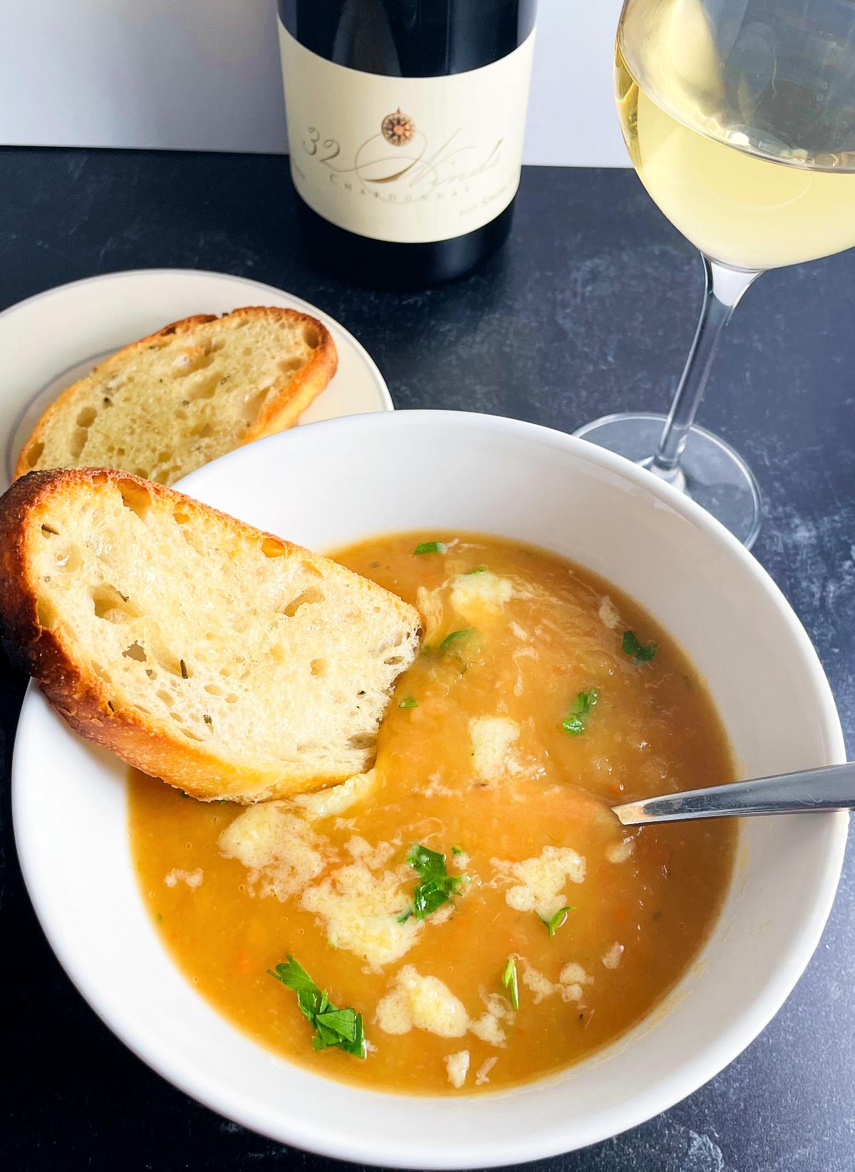 Irish vegetable soup served in a white bowl with toasted bread and a glass of Chardonnay.