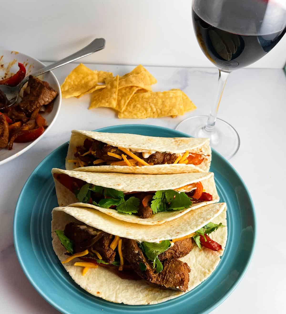 turquoise plate with leftover fajitas served with a glass of red wine.