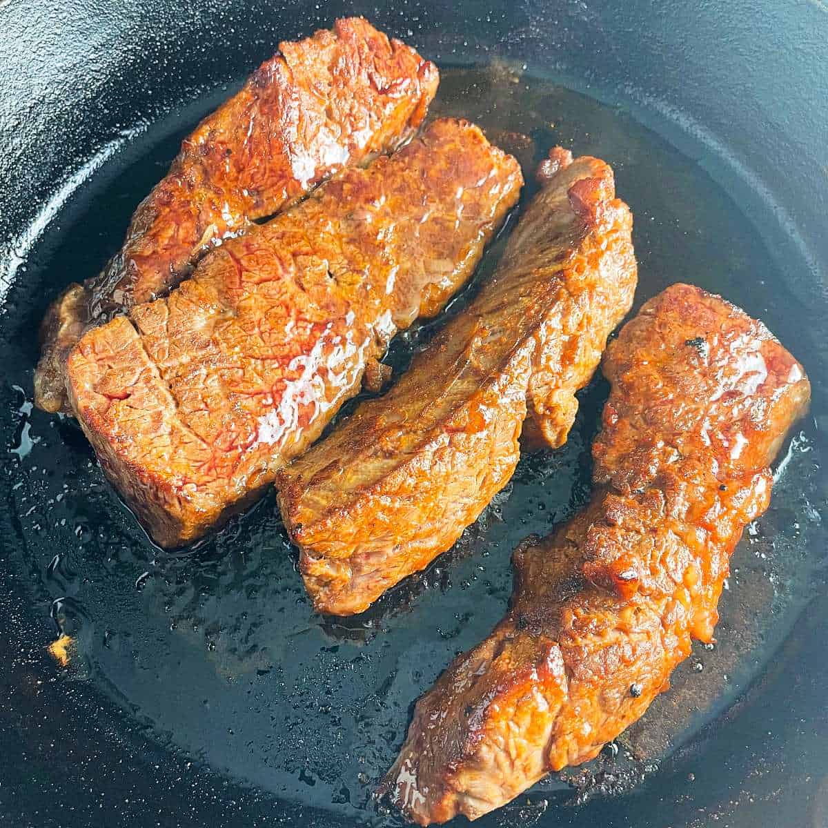 BBQ baked steak tips in a black skillet.
