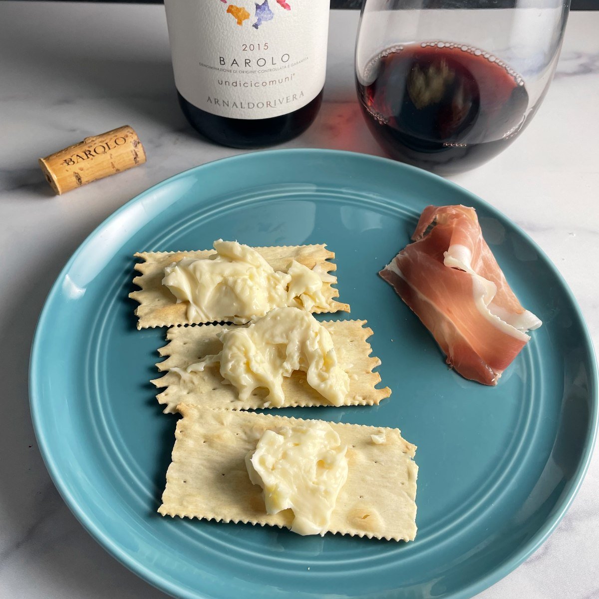 Taleggio cheese spread over crackers, served with prosciutto and a Barolo red wine.
