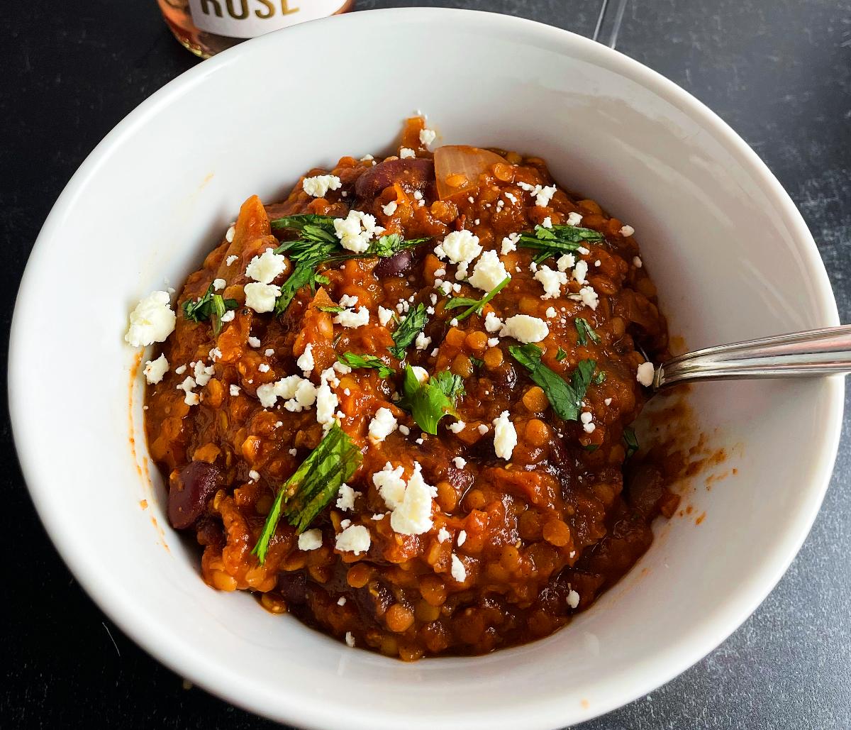 spicy lentil chili, topped with feta cheese and cilantro, served in a white bowl.