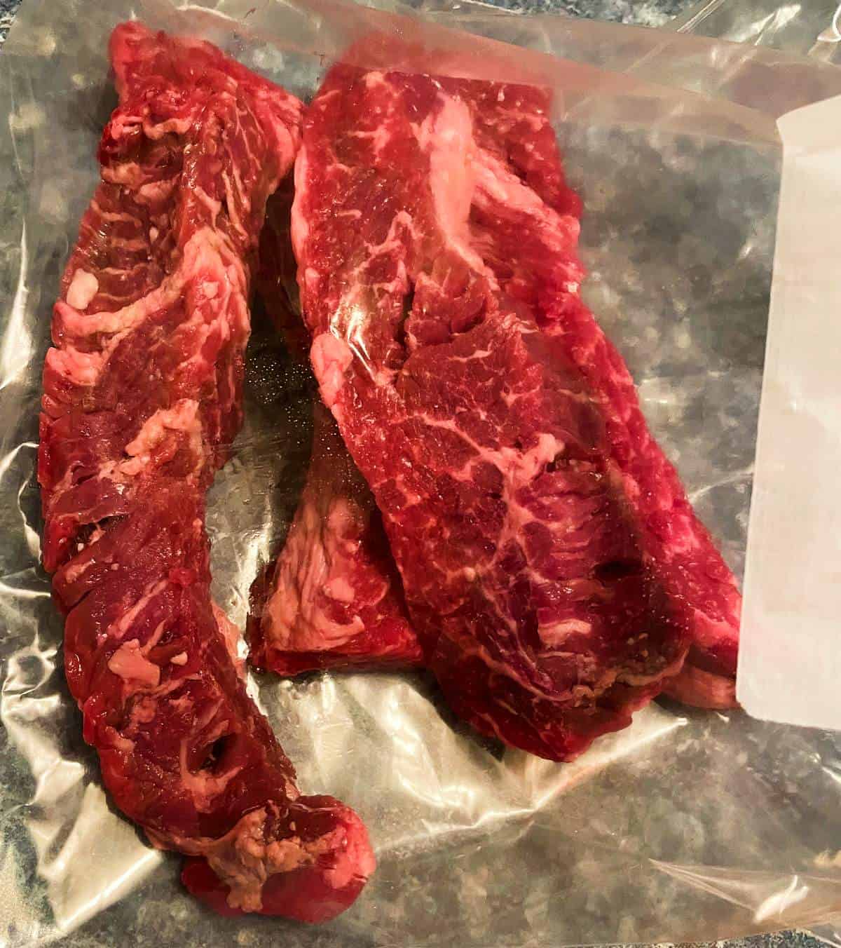 raw steak tips in a large plastic bag.