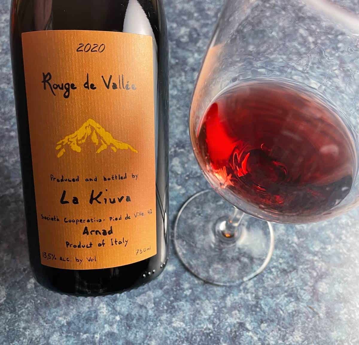 Bottle of La Kiuva Rouge de Vallée wine, with a glass of the red wine alongside the bottle.