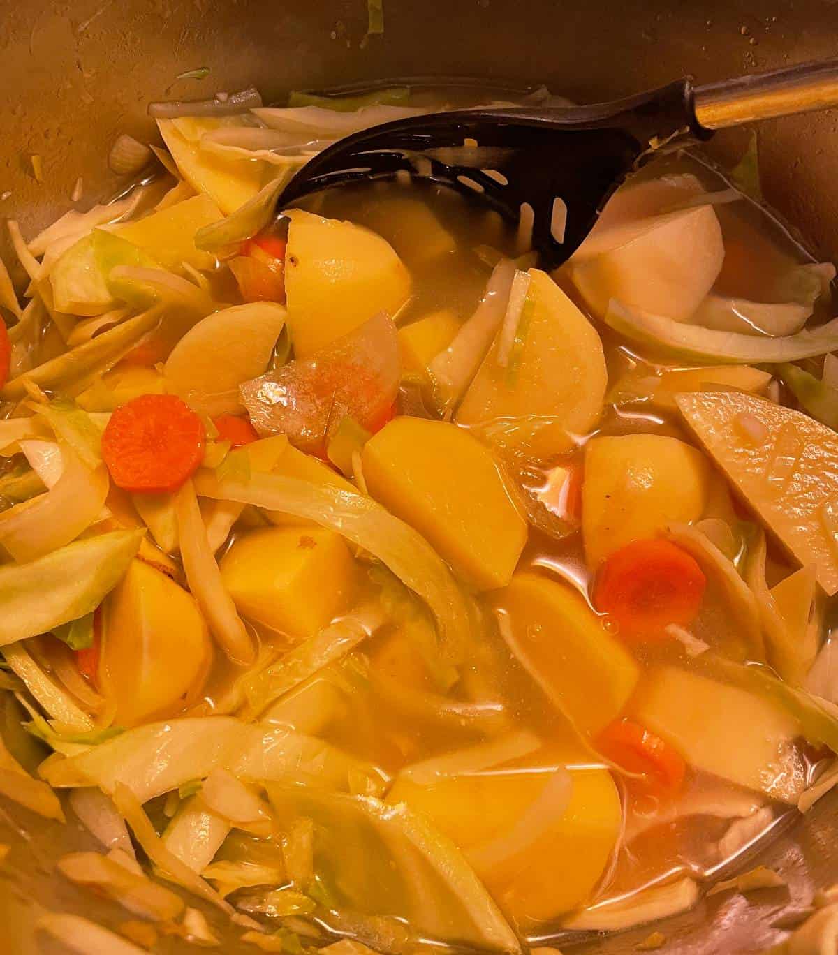 adding broth to potato soup pot.