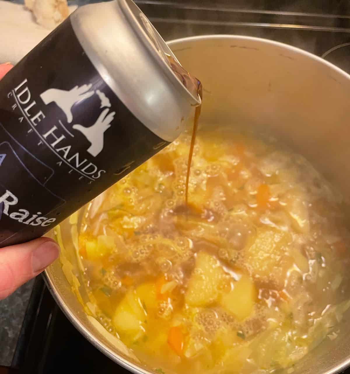 adding Idle Hands stout beer into a simmer pot of Irish potato soup.