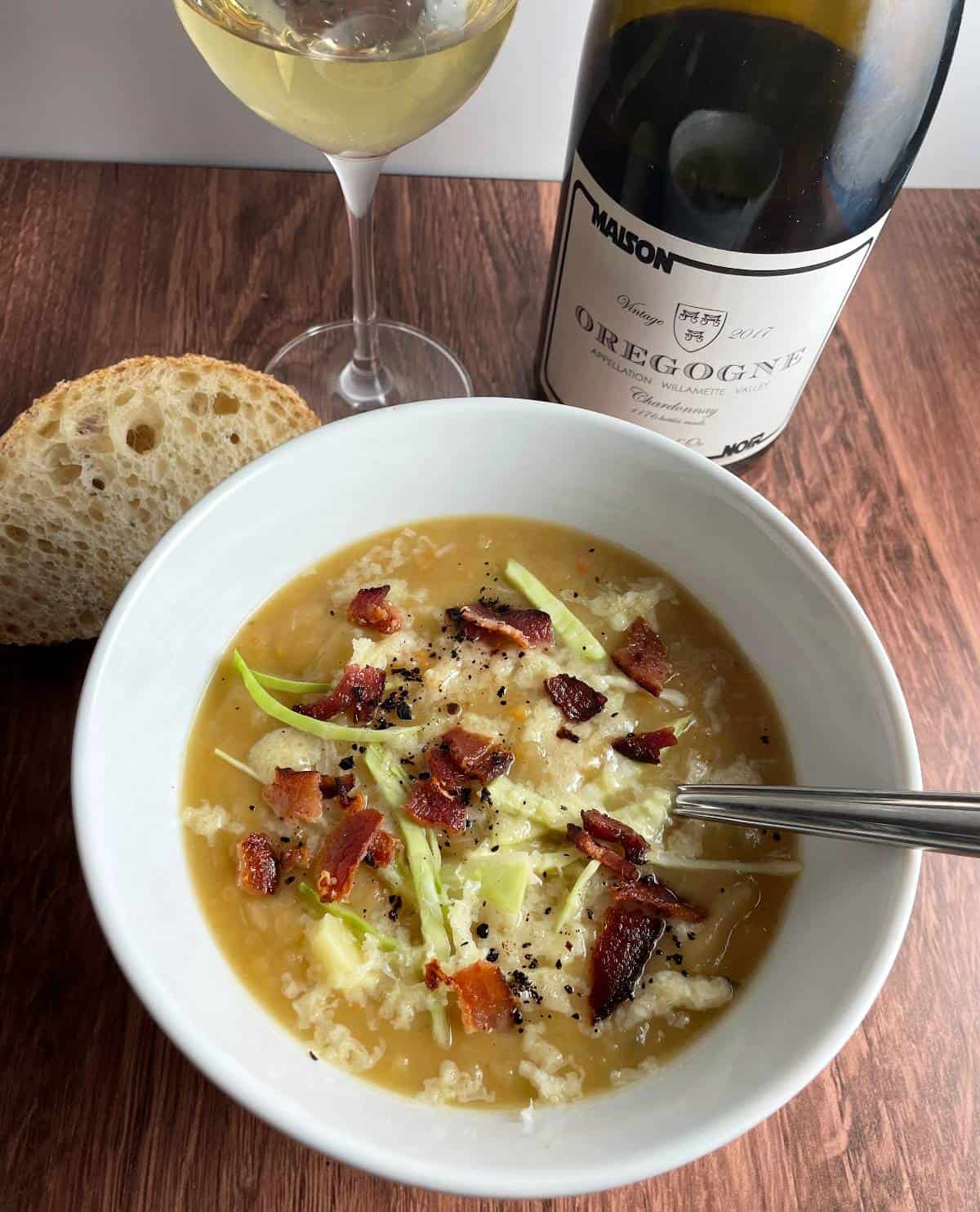 Bowl of Irish Potato Cabbage Soup topped with bacon and served with a Chardonnay.