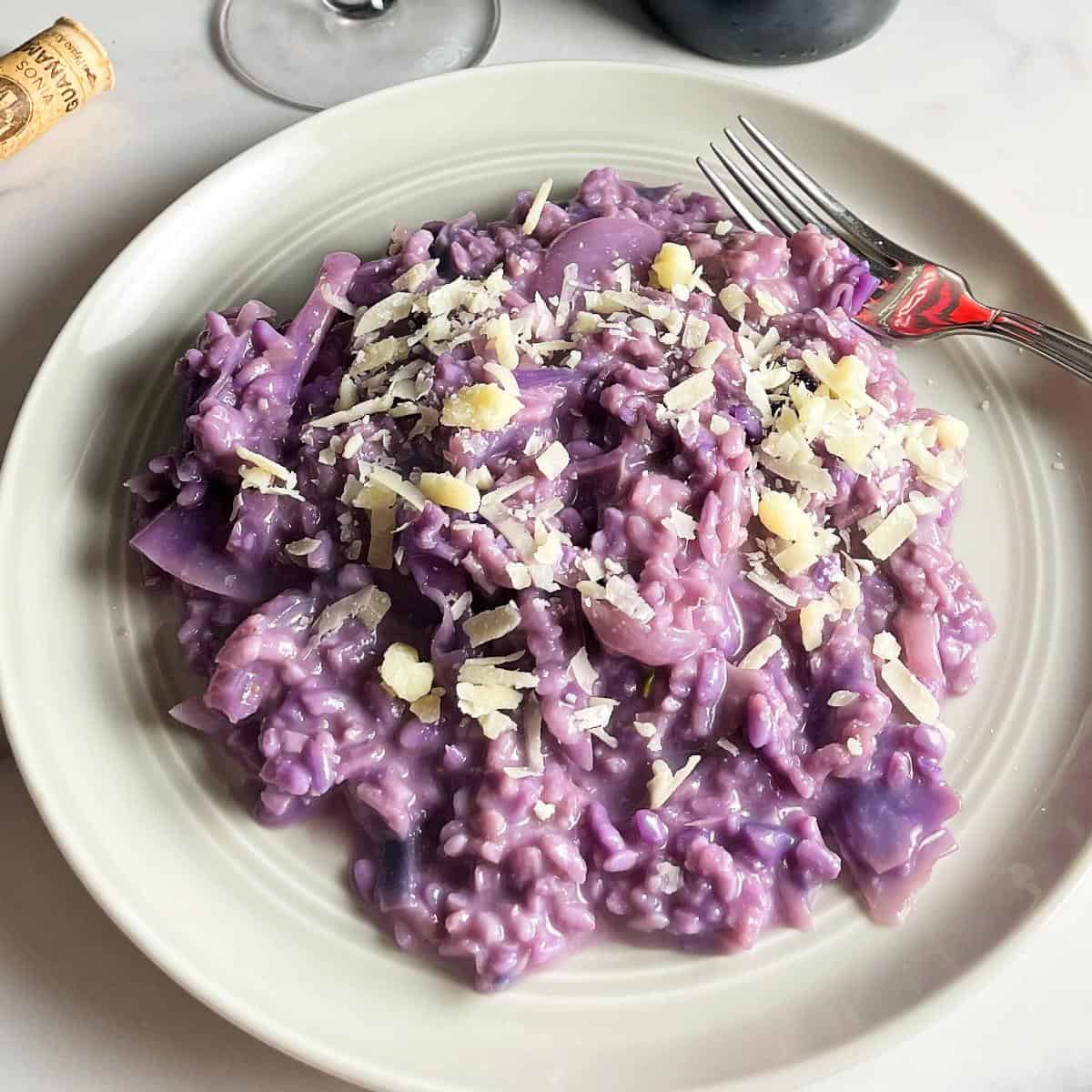 red cabbage risotto, served on a light grey plate, and topped with cheese.