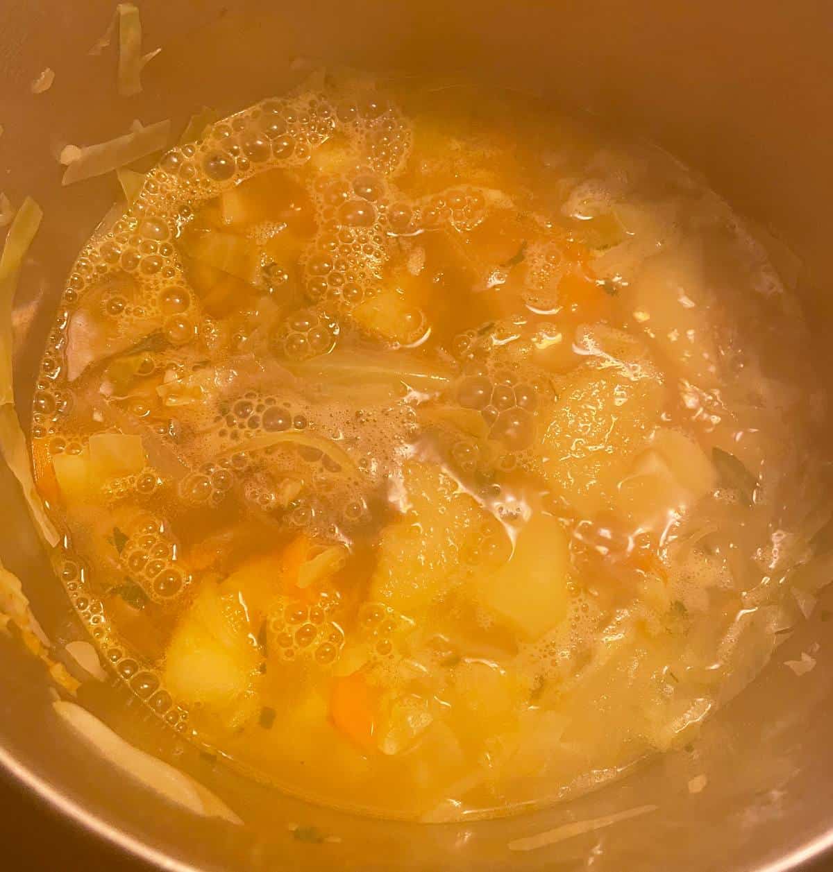 potato soup simmering after adding stout to the pot, making it darker in color.