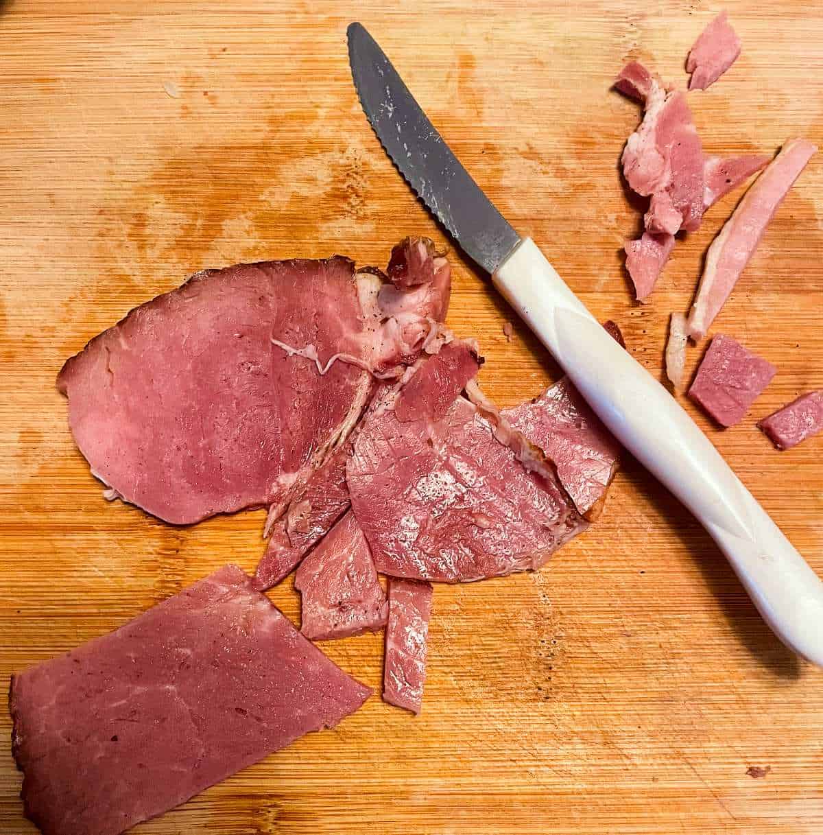 slices of ham on a wooden cutting board.